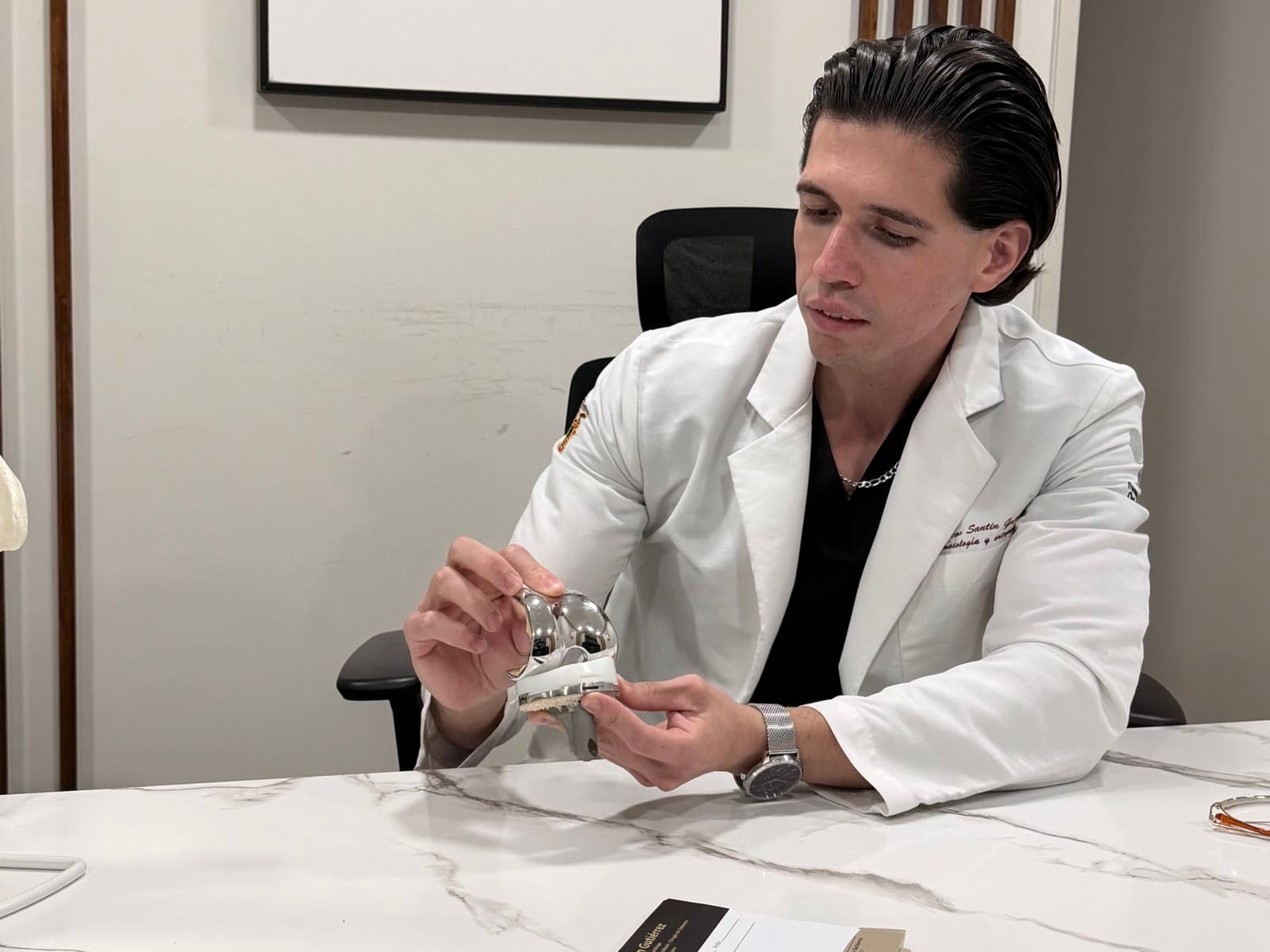 El Dr. Marcos Santin sosteniendo un componente de prótesis de rodilla
